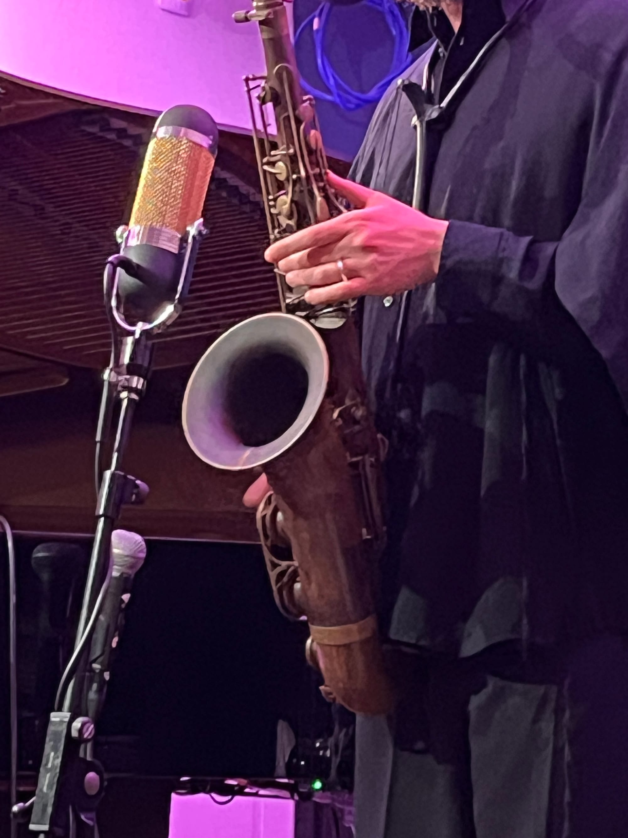 A closeup of a man’s left hand playing a tenor saxophone